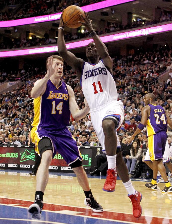 Philadelphia 76ers guard Jrue Holiday (11) shoots past the defense of Los Angeles Lakers forward Troy Murphy (14) during the third quarter of their NBA basketball game in Philadelphia, Pennsylvania February 6, 2012.(Xinhua/Reuters Photo) 