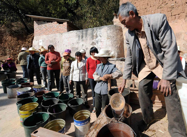 Zhang Xuexian distributes water at Zhangjiacun village in Chuxiong Yi autonomous prefecture, Southwest China's Yunnan province, Feb 8, 2012. The village has been hit by drought for the third consecutive year, driving people to travel more than 10 kilometers to get water. Local governments said they are applying for relief money to help with the problem. [Xinhua]