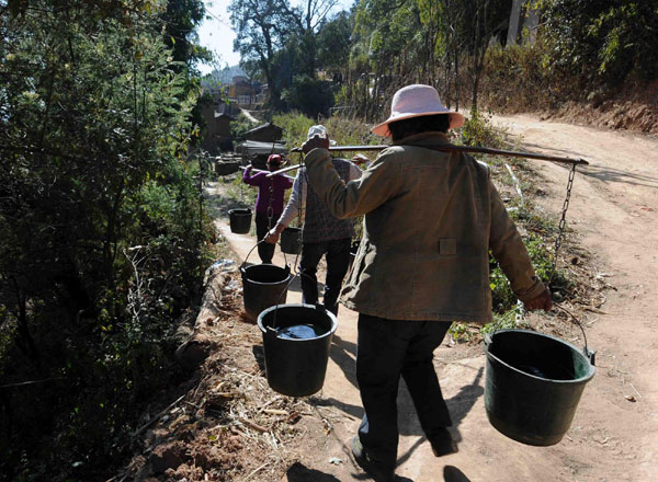 Women carry water home, Feb 8, 2012. [Xinhua]