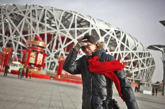 A tourist braves strong wind in Beijing on Monday. A large part of the country will experience colder than usual weather in the coming days, meteorologists said. [China Daily]