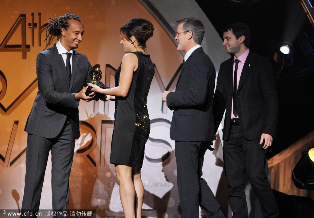 (L-R) Presenter Gerald Clayton, hands the award to Art Directors Michelle Holme and Dave Bett as they walk onstage to accept the Best Boxed or Special Limited Edition Package Award for The Promise: The Darkness on the Edge of Town Story (Bruce Springsteen) and presenter Brandon Heath looks on at the 54th annual Grammy Awards held at Staples Center on February 12, 2012 in Los Angeles, California.