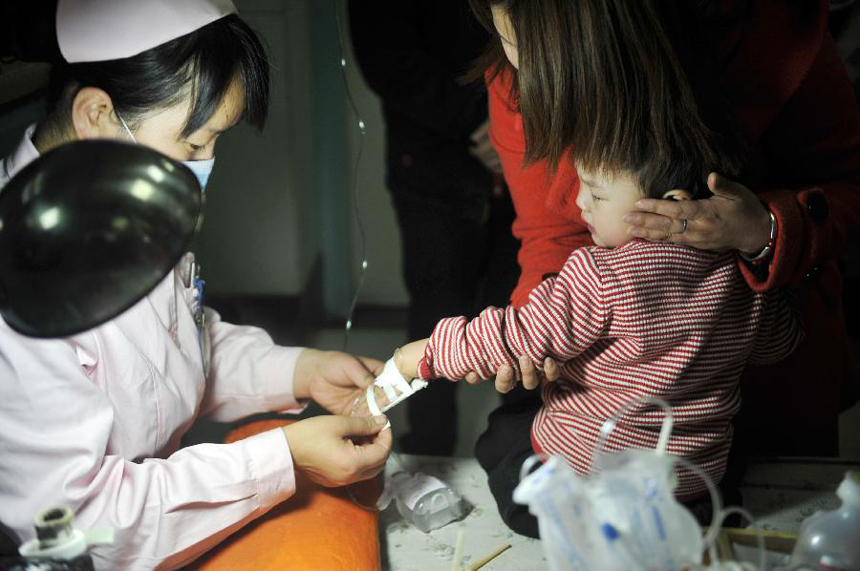 A nurse takes care of a child at Yinchuan Maternal and Children Health Hospital in Yinchuan, captial of northwest China&apos;s Ningxia Hui Autonomous Region, Feb. 12, 2012. Many children caught cold due to sharp temperture decline, rendering the number of children getting infusion to almost 300 people per day in the hospital. [Xinhua photo]