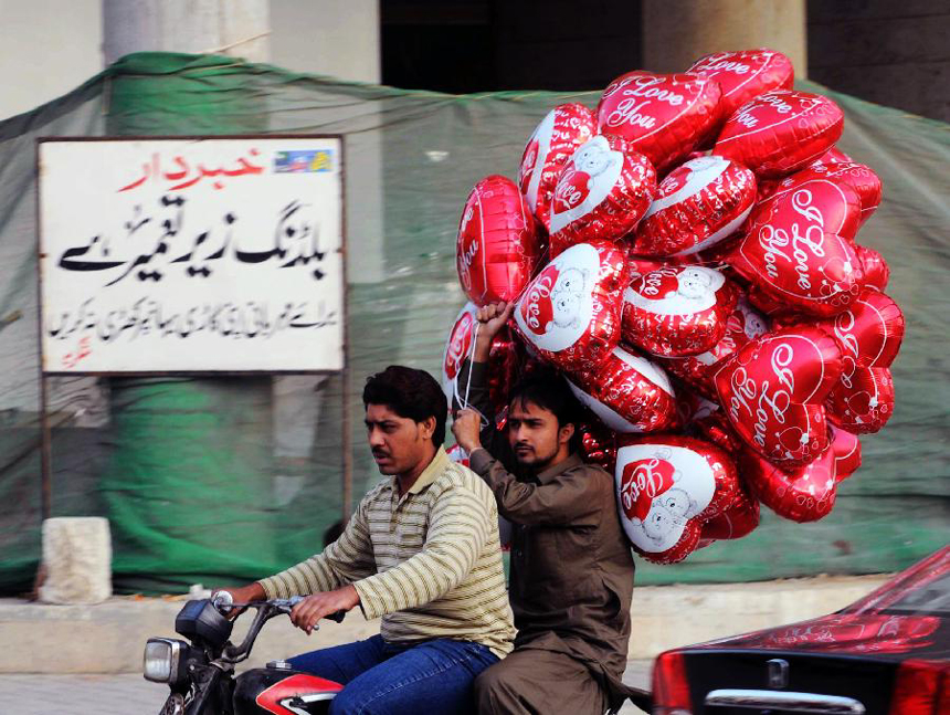 Motorbike riders carry heart-shaped balloons in southern Pakistani port city of Karachi on Feb. 13, the eve of Valentine's Day. 