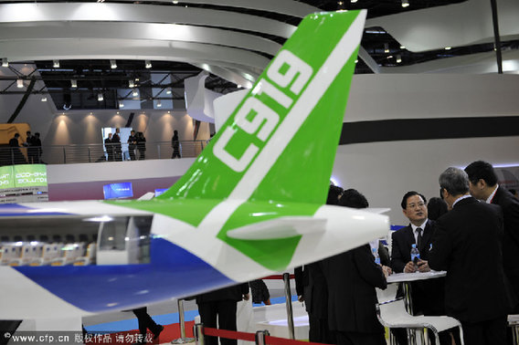 A model of a Commercial Aircraft Corp. of China C919 aircraft is displayed as Jin Zhuanglong, the company's chairman, background third right, speaks with guests at the Singapore Airshow in Singapore, on Feb. 14, 2012.[CFP]