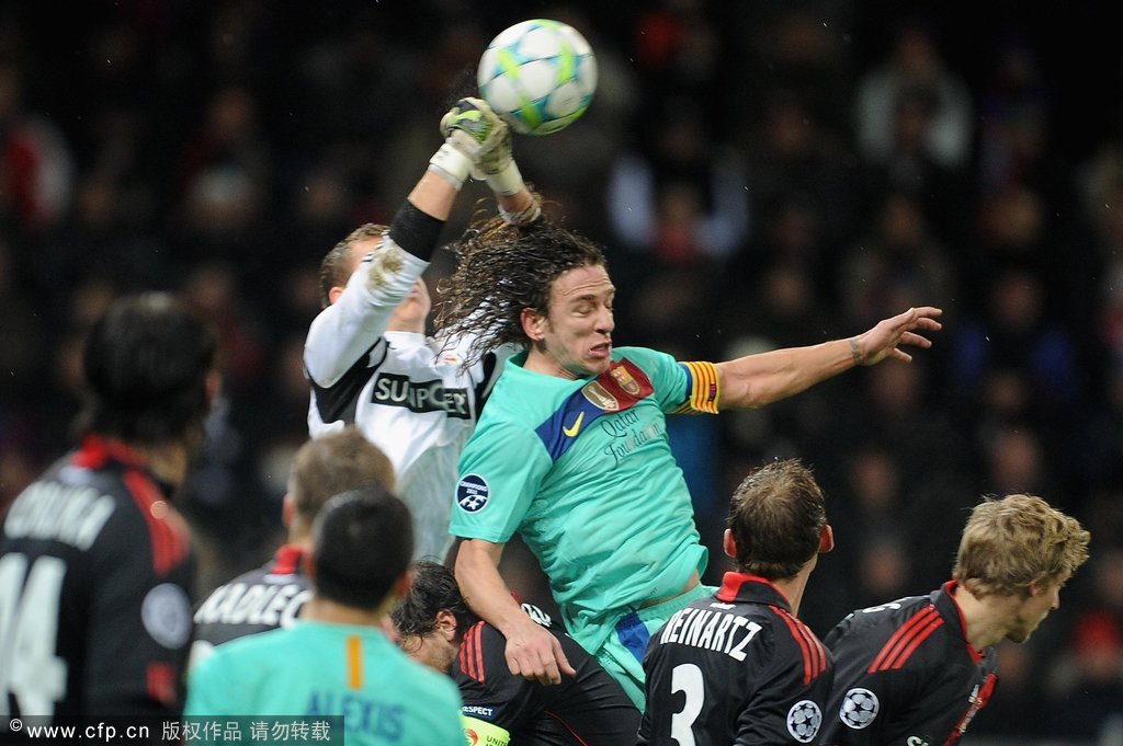 Goalkeeper Bernd Leno (L) of Leverkusen clears the ball under the pressure of Carlos Puyol (R) of Barcelona during the UEFA Champions League round of sixteen first leg match between Bayer 04 Leverkusen and FC Barcelona at BayArena on February 14, 2012 in Leverkusen, Germany. 