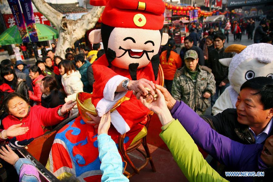 A performer acting as an avatar of the 'God of Wealth' in Chinese mythology distributes gifts for tourists at Fuzimiao, or the Confucius Temple, in Nanjing, capital of east China's Jiangsu Province, on Jan. 27, 2012. Various celebrations are held on the fifth day of the Chinese lunar New Year, which is considered as the birthday of the 'God of Wealth' in Chinese tradition.