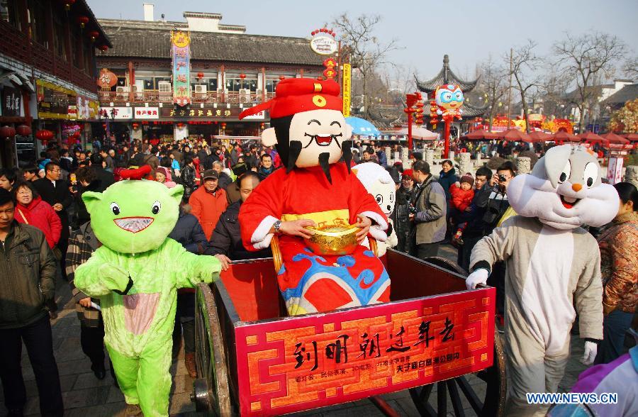 A performer acting as an avatar of the 'God of Wealth' in Chinese mythology is wheeled among tourists at Fuzimiao, or the Confucius Temple, in Nanjing, capital of east China's Jiangsu Province, on Jan. 27, 2012. Various celebrations are held on the fifth day of the Chinese lunar New Year, which is considered as the birthday of the 'God of Wealth' in Chinese tradition. 