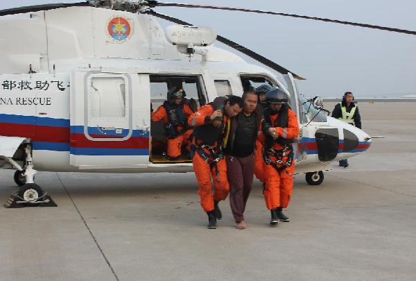 A surviving sailor is carried out of a helicopter in Quanzhou City, southeast China's Fujian Province, Feb. 18, 2012. A bulk cargo sank in the water area near Chongwu County of Quanzhou around 3:00 a.m. of local time Saturday. Eight sailors were confirmed dead and two were missing after rescuers saved one up to 1:00 p.m. Saturday of local time. [Liu Hui/Xinhua] 