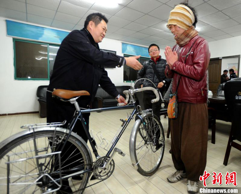 Keiichiro Kawahara (r) from Japan, who is engaged on a global cycling tour, gives thanks after his stolen bicycle is returned to him by the police in Wuhan City, capital of central China's Hubei Province, Feb. 20, 2012. 