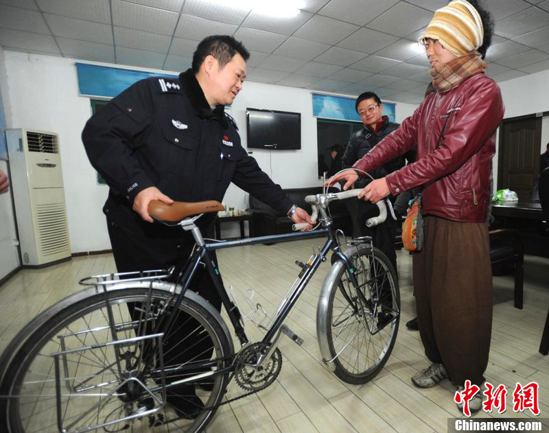 Keiichiro Kawahara (r) from Japan, who is engaged on a global cycling tour, takes possession of his modified bicycle after it is returned to him by the police after being stolen in Wuhan City, capital of central China's Hubei Province, Feb. 20, 2012. 