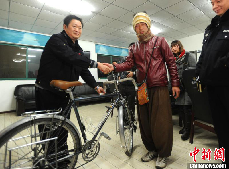 Keiichiro Kawahara (r) from Japan, who is engaged on a global cycling tour, poses for media pictures after his stolen bicycle is returned to him by the police in Wuhan City, capital of central China's Hubei Province, Feb. 20, 2012. 