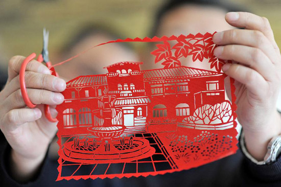 Li Qiang, a kirigami artist, shows his paper-cutting work with the theme of western-style houses in Tianjin Municipality, north China, Feb. 17, 2012. A series of paper-cutting craftworks with the theme of western-style houses were created by local artists recently, to display the history and culture of the city. (Xinhua/Wang Xiaoming)