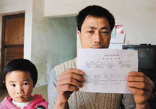 Liu Hongdai, a resident of Dongtang township, holds up a body check sheet of one of his granddaughters who had been diagnosed with excessive lead in blood on Wednesday. [China Daily] 