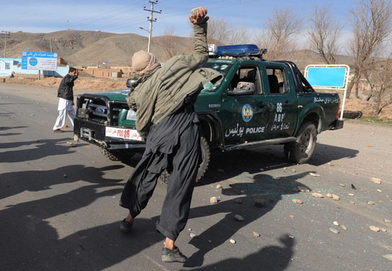 Afghan people throws stone at a police car as people protest against the alleged Quran burning by U.S. troops in Herat, west Afghanistan, on Feb. 24, 2012. At least 15 people including two U.S. soldiers have been killed and over 50 others injured since violent protests began Tuesday and swept across the country. [Xinhua/Sardar]