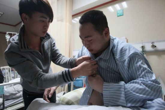 2月17日晚，广州市第十二人民医院。躺在病床上两个多月的吴兵兵仍然不能自己解开衣服扣。记者 孙振飞 摄