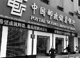 Pedestrians walk past a branch of the Postal Savings Bank of China in Yichang city, Hubei province, on Monday. The commercial bank has finished a joint-stock restructuring and prepared for a sale of shares to the public. [China Daily]