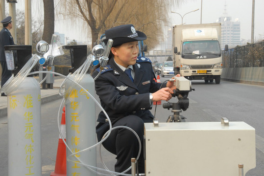 Zhang Zhijie, an emission management official with the environmental protection bureau of Chaoyang district in Beijing, tests monitoring equipment near a park on Tuesday. [China Daily] 