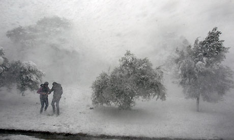 A couple seek shelter during a heavy snowfall on the mountain of Penteli in northern Athens. [Agencies] 