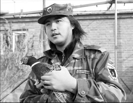 Li Li, 29, founder of the Black Leopard Wildlife Conservation Station, a non-governmental organization in Beijing, holds a rescued pheasant at a branch station in Nanhe village, Beijing's Fangshan district, on Feb 15. [China Daily] 