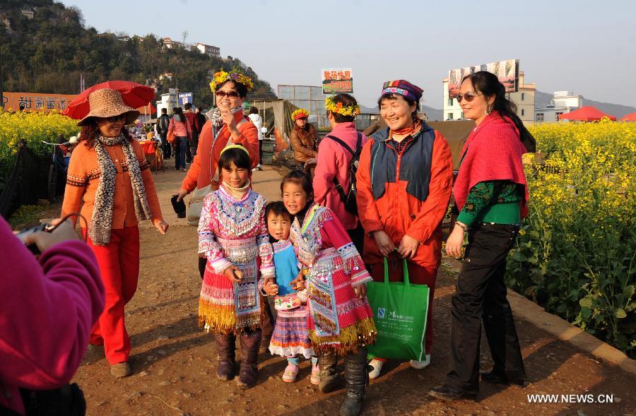 Tourists pose for photos with local children near the field of cole flowers in Luoping County, southwest China's Yunnan Province, Feb. 29, 2012. More than 53,000 hectares of cole flowers in Luoping entered the blossom season recently. (Xinhua/Qin Qing) 
