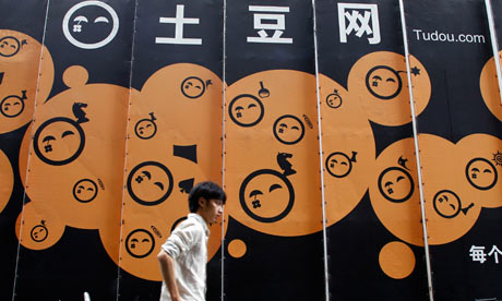 A pedestrian walks past the logo of Tudou. [File pohto]