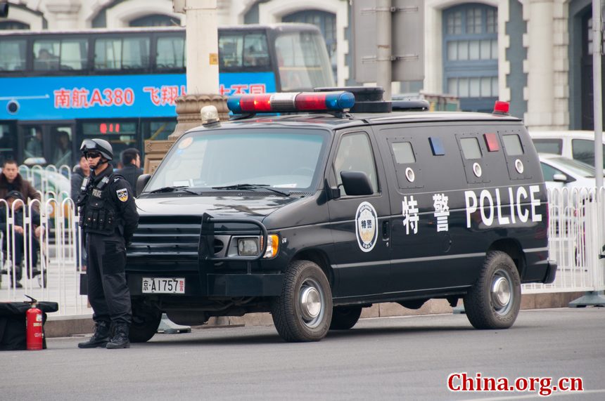 A police officer with the SWAT unit stands on guard before an armoured vehicle near the Great Hall of the People shortly before the opening ceremony of CPPCC takes place on Saturday afternoon. [China.org.cn]