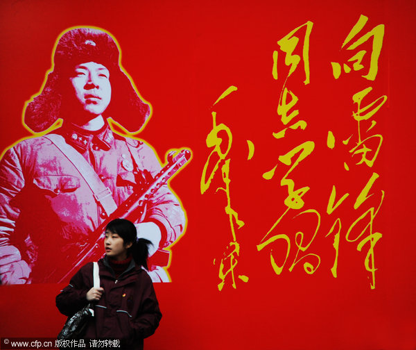 A woman passes a wall with a portrait of Lei Feng near a bookstore in Shanghai, March 3, 2012. [Photo/CFP] 