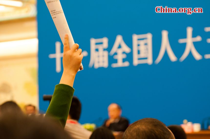 A woman journalist holds a paper roll as she raises her hands so as to catch the organizer&apos;s attention. [China.org.cn]