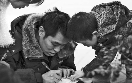 A boy guiding his father as he fills in an application form for a job at a Chinese company's overseas project while the boy's mother looks on. Many of these projects are in Africa and other developing economies, where, because of a shortage of material goods, there isn't much to spend money on so many send much of their earnings back home. [China Daily]