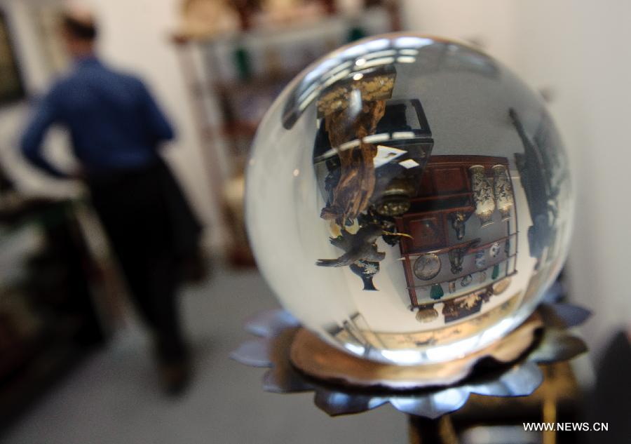 A crystal ball reflects items displayed at the 32 session of Russian International Exhibition of Antiques in Moscow, capital of Russia, March 9, 2012. Some 200 exhibitors attended the exibition which opened on Friday. (Xinhua/Jiang Kehong) 