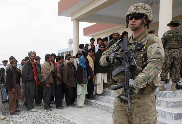 A US soldier stands guard as former Taliban members hand over their weapons as part of the Afghan government's reconciliation program in Laghman province on Monday. Tension in the country has risen sharply after the Taliban vowed revenge on Monday for an 'inhumane attack' in which an American soldier allegedly killed 16 villagers in Kandahar province. [Photo by Parwiz / Reuters]