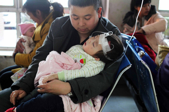 A father cradles his daughter as she is treated at the Beijing Pediatric Research Institute on Monday. The government has vowed to boost medical reform amid growing public demand for better services. [China Daily] 