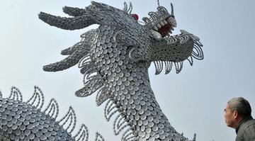 A man looks at a dragon statue made of porcelain in Jingdezhen of east China's Jiangxi Province, March 12, 2012. A dragon statue made of over 40,000 pieces of ceramic wares is seen on the Renmin square here on Monday. Jingdezhen is also known as a porcelain making center in China. (Xinhua/Shi Weiming)