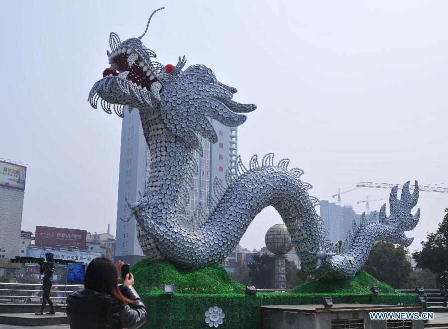 A woman takes photo of a dragon statue made of porcelain in Jingdezhen of east China's Jiangxi Province, March 12, 2012. A dragon statue made of over 40,000 pieces of ceramic wares is seen on the Renmin square here on Monday. Jingdezhen is also known as a porcelain making center in China. (Xinhua/Shi Weiming)