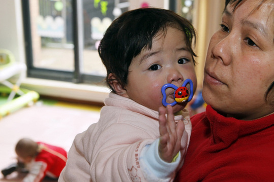 A worker at Lupin Foster Home holds a little girl in Shanghai on Feb 28. The foster home, an NGO, opened a year ago to care for sick, orphaned infants from remote areas of China and to offer a free, cozy place in which they may recover. [China Daily] 