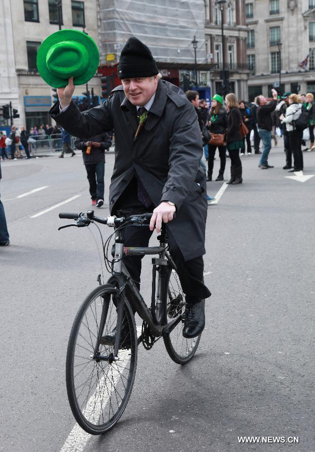 London Mayor Boris Johnson waves his hat as he rides a bike in central London, Britain, March 18, 2012. St. Patrick's Day is a religious holiday celebrated internationally on March 17. It is named after Saint Patrick, the most commonly recognized of the patron saints of Ireland. (Xinhua/Xiang Mei)