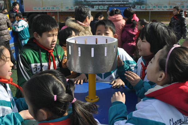 School kids are fascinated by the exhibits brought by Qin Ruiqiang's mobile science caravan, at a school playground in Zhengding county, Hebei province. Provided to China Daily