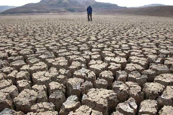 A villager walks on the dried-up bed of the Xinba reservoir in Shilin County, China's Yunnan Province, March 22, 2012. A severe drought has lingered in Yunnan for three consecutive years. [Xinhua] 