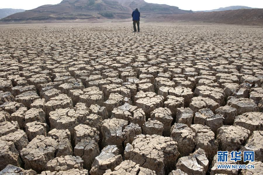 A villager walks on the dried-up bed of the Xinba reservoir in Shilin County, southwest China's Yunnan Province, March 22, 2012.