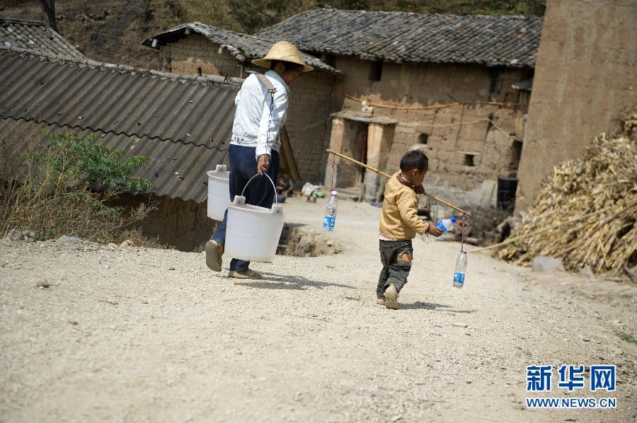 A boy carries water with his mother in Dayeshan Village of Shilin County, southwest China's Yunnan Province, March 22, 2012. 