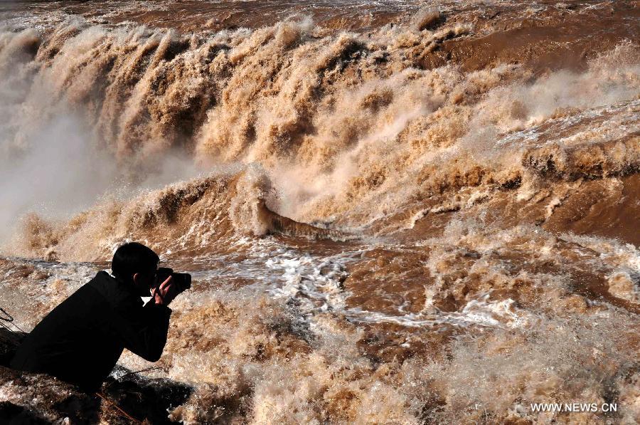 A visitor takes photos of the Hukou Waterfall of Yellow River in Jixian County, north China's Shanxi Province, March 24, 2012. The period from March to April, when peach flowers blossom, is one of the best times to view the Hukou Waterfall. (Xinhua/Lu Guiming) 