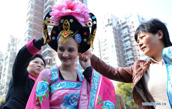 An Ukrainian student (C) wears headgear of Huangmei Opera in Keqi Community of Hefei, capital of east China's Anhui Province, March 26, 2012. The community invited professional Huangmei Opera performers to give a lesson on Monday, to greet the World Theatre Day that falls on March 27. (Xinhua/Liu Junxi)