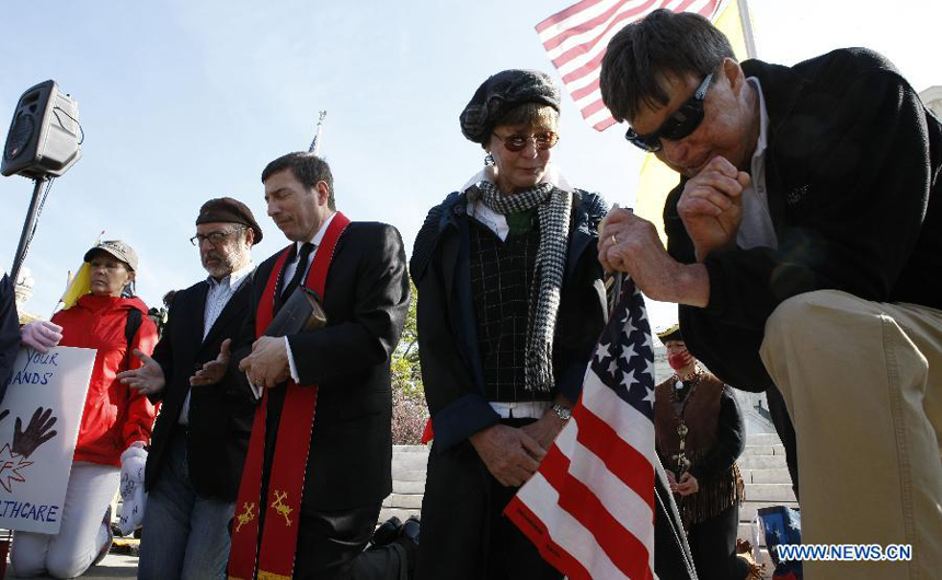 A man prays during a protest in front of the U.S. Supreme Court building in Washongton D.C., capital of the United States, on March 28, 2012. The U.S. Supreme Court on Wednesday entered its last day of oral arguments in the landmark case involving the Affordable Care Act, the signature healthcare overhaul of President Barack Obama.