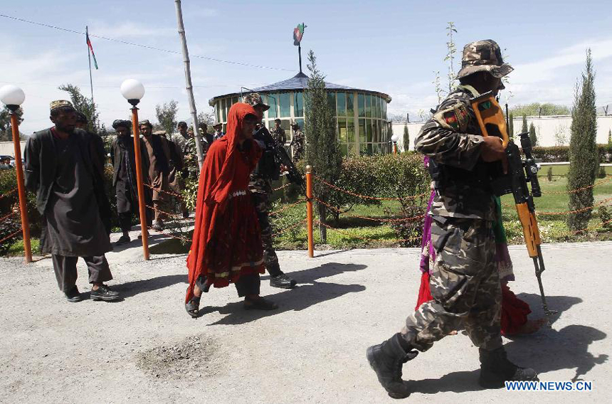 Afghan security forces escort the Taliban fighters who wearing the traditional women clothes to show for the media after being captured by the Afghan national security forces in Laghman Province, east of Kabul, capital of Afghanistan on March 28, 2012. Seven male Taliban fighters wearing female clothes captured by Afghan security forces during their operations in Laghman Province, official said. 