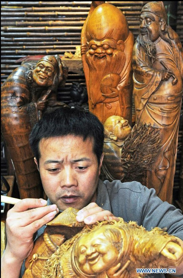 Wang Shuhong, a sculptor, makes a fisherman's figurine using a bamboo root in Anji County, east China's Zhejiang Province, March 30, 2012. (Xinhua/Tan Jin) 