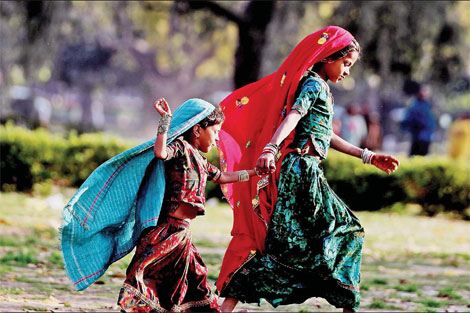 Two girls run in a street of Delhi on Feb 25. Photos by Wang Jing / China Daily