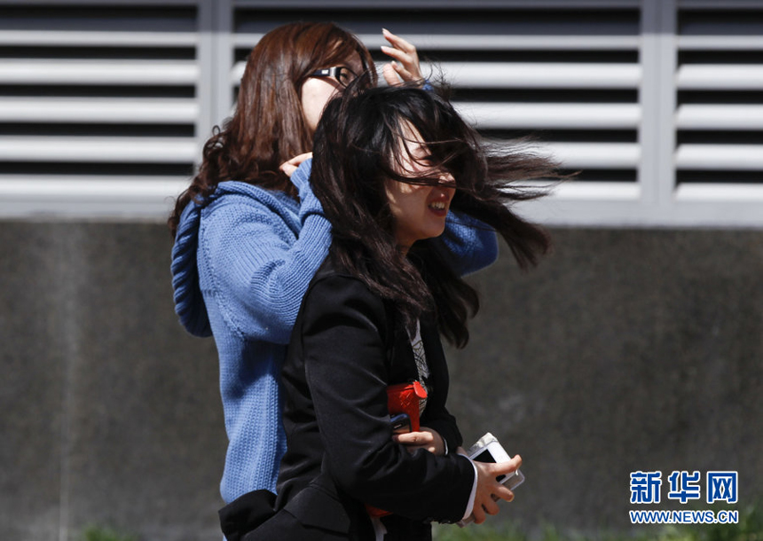 Two women walk against the gale in downtown Beijing, April 5. Meteorologists issue a strong wind warning early today. 