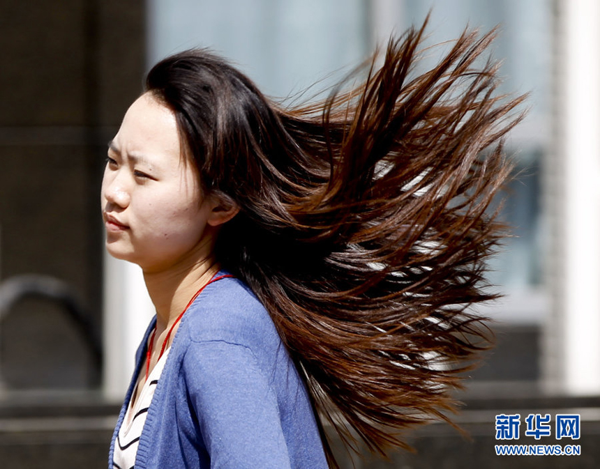 A girl walks against the gale in downtown Beijing, April 5. Meteorologists issue a strong wind warning early today. 