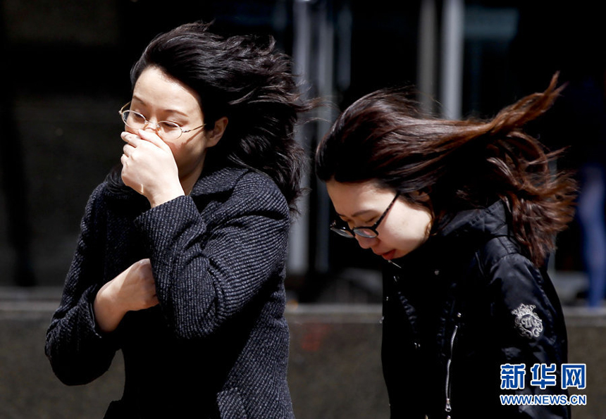 Two women walk against the gale in downtown Beijing, April 5. Meteorologists issue a strong wind warning early today. 