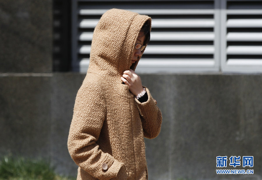A woman walks against the gale in downtown Beijing, April 5. Meteorologists issue a strong wind warning early today. 